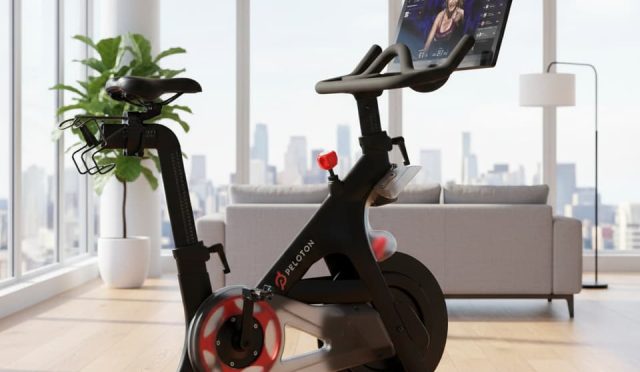 Peloton exercise bike in a bright modern living room with wooden floors, natural light, and minimalistic décor for a fresh home workout setup.